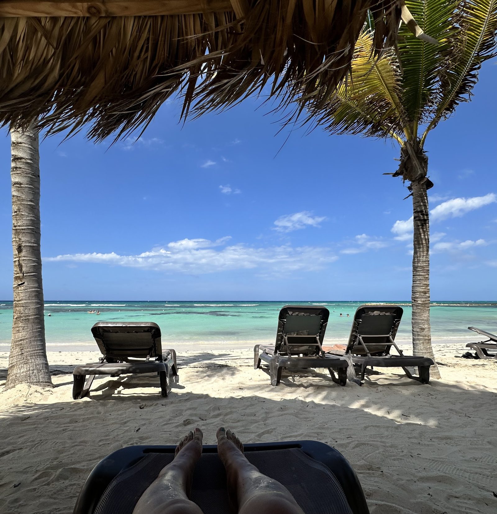 Beachfront in Jamaica, palm-thatched shade over lounge chairs